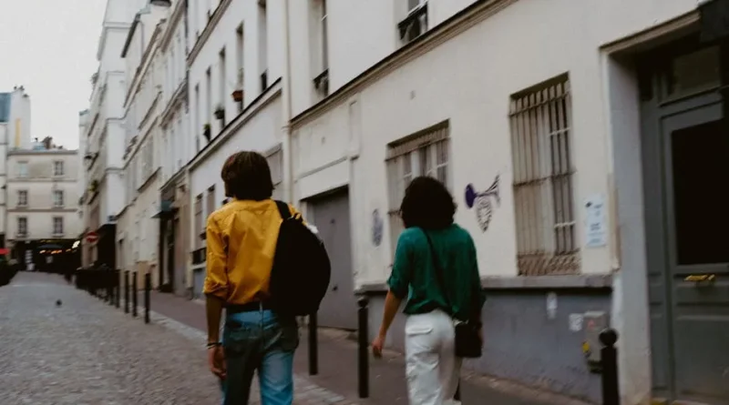 A stylish traveler pulling a compact carry-on suitcase through a scenic European cobblestone street.