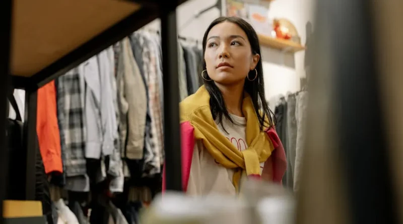 A curated selection of neutral-toned clothing items laid out on a clean wooden floor