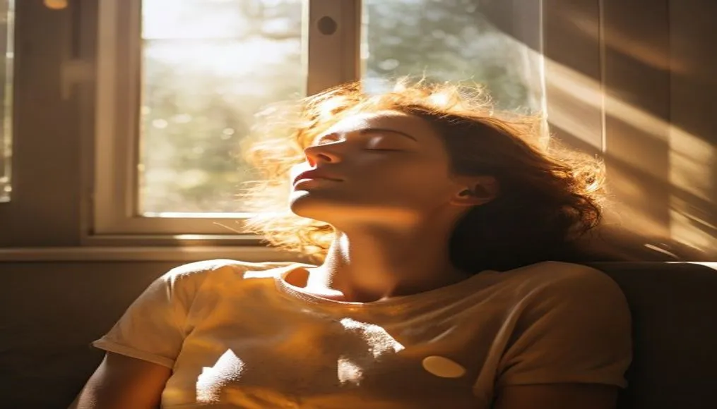 Person relaxing with eyes closed, sunlight streaming in